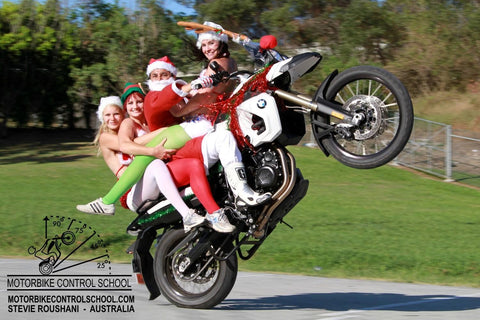 Four people dressed up in Christmas costumes doing a wheelie on one bike. 