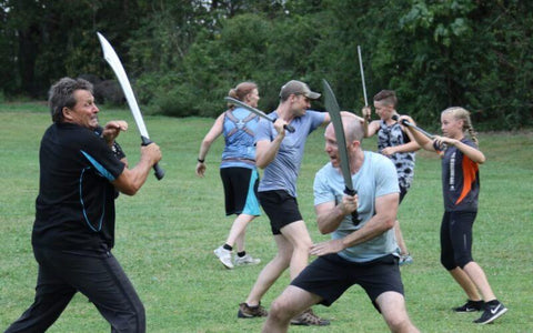 Group of six people engaging in a stunt sword fighting battle. 